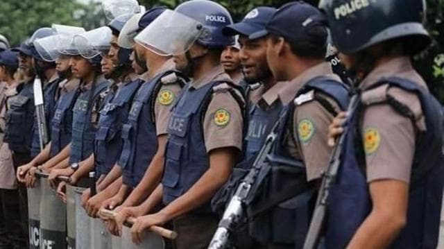 কয়েকজন পুলিশ সদস্য ইউনিফর্মের ওপর ভেস্ট পরে শিল্ড নিয়ে দাঁড়িয়ে আছেন